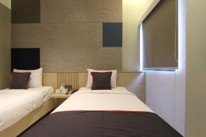 twee bedden naast elkaar in een kamer bij IXO Hotel Semarang in Stasiun Tawang