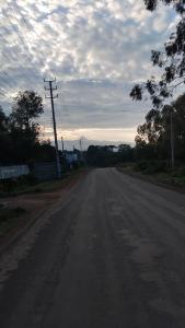 an empty road with a cloudy sky in the distance at Hellena house in Nanyuki