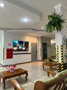 ein Wohnzimmer mit einem Flachbildfernseher an der Wand in der Unterkunft Hotel Lux in Poços de Caldas + 40 Fotos