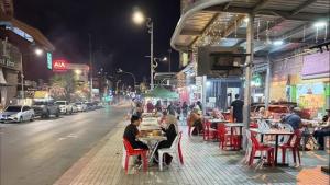a group of people sitting at tables on a street at night at Watermelon Hotel in Miri