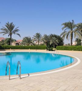 a swimming pool with palm trees in the background at Akasha Villa in Madīnat ash Shurūq