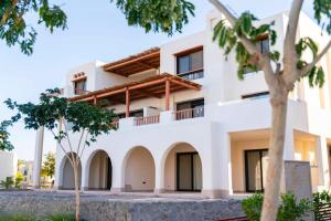 Un edificio blanco con árboles delante. en Makadi Heights Elite Worldwide Residences - Hurghada, Egypt, en Hurghada