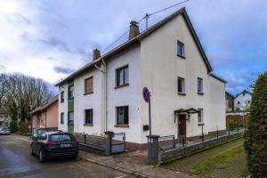 une voiture garée devant une maison blanche dans l'établissement Charming apartment in Miesenheim, à Andernach