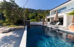 a swimming pool in front of a house at Villa Palazzo Maestral beachfront by Villas Guide in Viniština