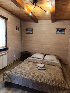 ein Schlafzimmer mit einem Bett in einem Zimmer mit Holzwänden in der Unterkunft Котедж Арніка in Worochta
