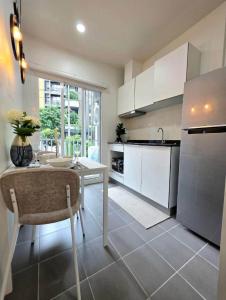 une cuisine avec une table et des placards blancs dans l'établissement The Modern central Phuket base condo by luxStays, à Ban Rangeng