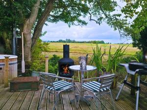 een patio met een tafel en stoelen en een fornuis bij The Pheasant in Great Ellingham
