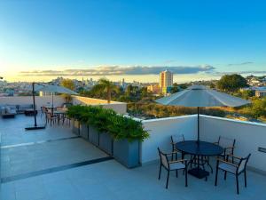 a balcony with tables and chairs and a view of the city at Tupis Flats 1401 in Belo Horizonte