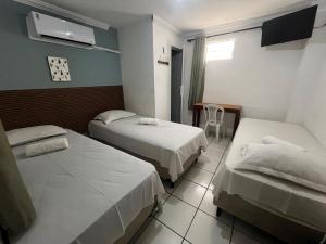 ein Hotelzimmer mit zwei Betten und einem Tisch in der Unterkunft Pousada Executiva in Teresina
