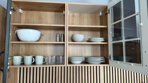 a wooden cabinet with plates and bowls in it at Meyben Apartment Mannheim Küche, TV, Waschmachine in MHG +12 photos