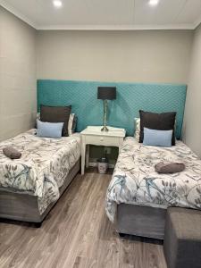 ein Schlafzimmer mit zwei Betten und einem Tisch mit Lampe in der Unterkunft Meadow Lane Country Cottages in Underberg