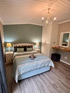 ein Schlafzimmer mit einem großen Bett und einem Kronleuchter in der Unterkunft Meadow Lane Country Cottages in Underberg