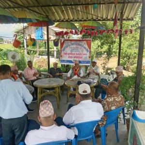 a group of men sitting at tables under an umbrella at Ecopark Homestay in Bharatpur