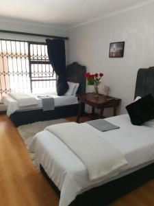 ein Schlafzimmer mit 2 Betten und einem Tisch mit Blumen in der Unterkunft Long Avenue Guest House in Johannesburg