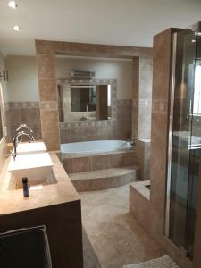 ein Badezimmer mit Badewanne, Waschbecken und Dusche in der Unterkunft Long Avenue Guest House in Johannesburg