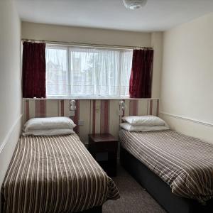 Dos camas en una habitación pequeña con ventana. en The Old Lamb, en Reading 12 fotos más