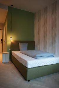 Un dormitorio con una cama con una pared verde. en qnorke Hotel, en Berlín