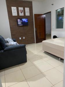 a bedroom with a bed and a couch and a tv at Casa Bela Vista II in São Roque de Minas
