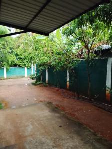 an empty parking lot with a fence and a tree at Wandana Holiday Home in Anuradhapura