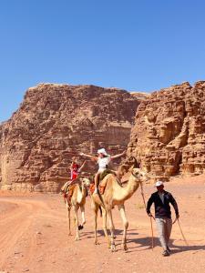 a group of people riding on camels in the desert at Lunara Desert Luxury Camp in Wadi Rum