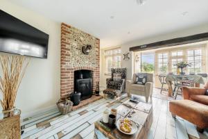 a living room with a brick fireplace and a table at Sunset View in Thornham