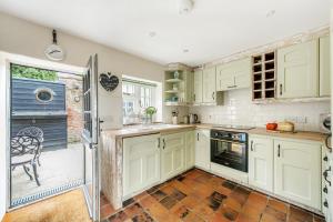 a kitchen with white cabinets and an open door at Sunset View in Thornham +14 photos
