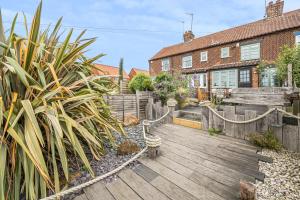 a garden with a wooden deck in front of a house at Sunset View in Thornham