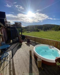 ein Whirlpool auf einer Terrasse mit Blick auf ein Feld in der Unterkunft Beautiful dog friendly lodge with hot tub in Aboyne + 16 Fotos