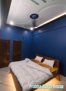 a blue bedroom with a bed and a ceiling at Prabha Guest House Ayodhya in Ayodhya