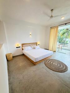 a bedroom with a bed and a large window at OLA Tangalle in Tangalle
