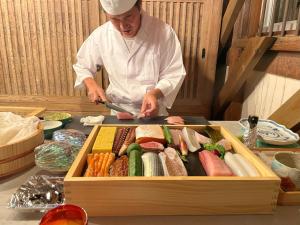 a chef preparing food in a wooden box at 3000平米の元醤油名家邸宅, 日本庭園, 蔵Bar, サウナ, 出張料理, フルサービスの宿 in Shodoshima