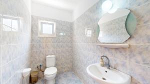 ein Badezimmer mit Waschbecken, Toilette und Spiegel in der Unterkunft Villa Olivia in Lapithos + 13 Fotos