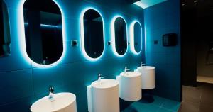 a bathroom with three sinks and four mirrors at Wostel The Comfort Hostel in Málaga