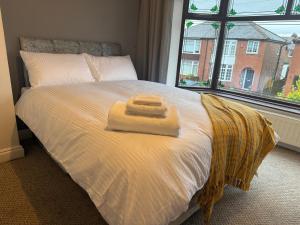 a bed with two towels on it with a window at chesterton Grove in Manchester