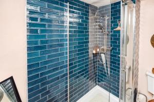 a blue tiled shower in a bathroom at Snowdrop Cottage in Jacobstowe