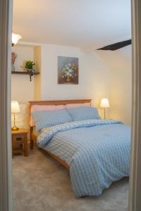 a bedroom with a bed with a blue comforter at Snowdrop Cottage in Jacobstowe