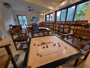 Una mesa de billar en una habitación con mesas y sillas. en Coastal Suites Apart Hotel ---- 12 minutes walk to beach, en Benaulim