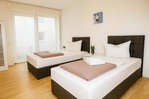two beds in a room with white walls and wood floors at SUNNYHOME Monteurwohnungen und Apartments in Schwandorf in Schwandorf in Bayern +3 photos