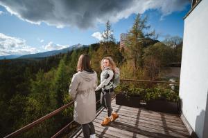 two women standing on a balcony looking at each other at Vila Emma in Štrbské Pleso