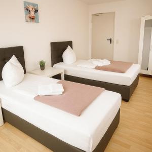 two beds in a room with white and brown at SUNNYHOME Monteurwohnungen und Apartments in Schwandorf in Schwandorf in Bayern