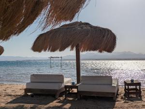 two chairs and an umbrella on the beach at Panoramic Seaview Somabay 1BR Apartment in Mesca in Hurghada