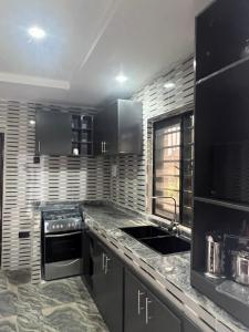 a kitchen with black cabinets and a sink at GG suites and Apartments in Owerri