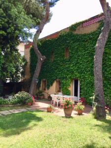 ein von grünem Efeu bedecktes Gebäude mit einem Tisch im Hof in der Unterkunft Casa de pueblo con jardín in Premiá de Mar