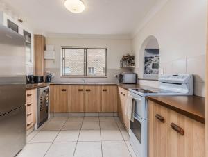 a kitchen with wooden cabinets and white appliances at Layback on Marine in Kingscliff