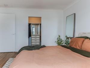 a bedroom with a large bed with an orange bedspread at Layback on Marine in Kingscliff