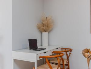 a white desk with a laptop and a vase with a feather at Layback on Marine in Kingscliff +12 photos