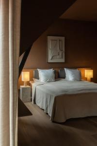 a bedroom with two beds with white sheets and two lamps at Audo Boutique Hotel in Copenhagen