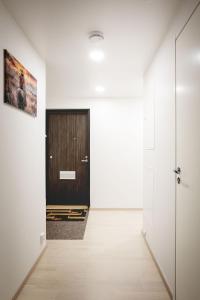 a hallway with a wooden door in a white room at Cozy Seaside Apt near Helsinki Harbour -Jätkäsaari in Helsinki