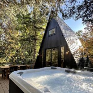 a black house with a tub in front of it at Lovely Secluded A-frame with Hot-tub in Sundance, Utah in Sundance