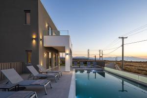 a swimming pool with lounge chairs and a house at MiNo Mare modern Sea View Villa with Pool up to 12 in Panormos Rethymno